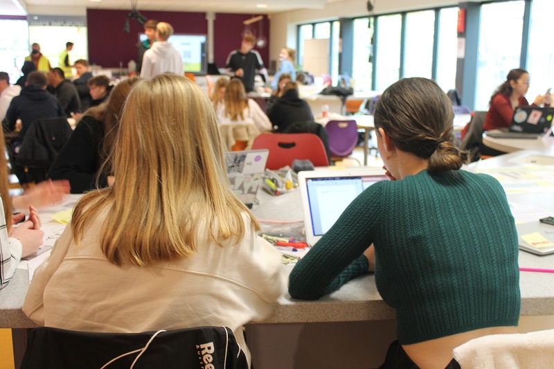 leerlingen werken aan een laptop in een klas