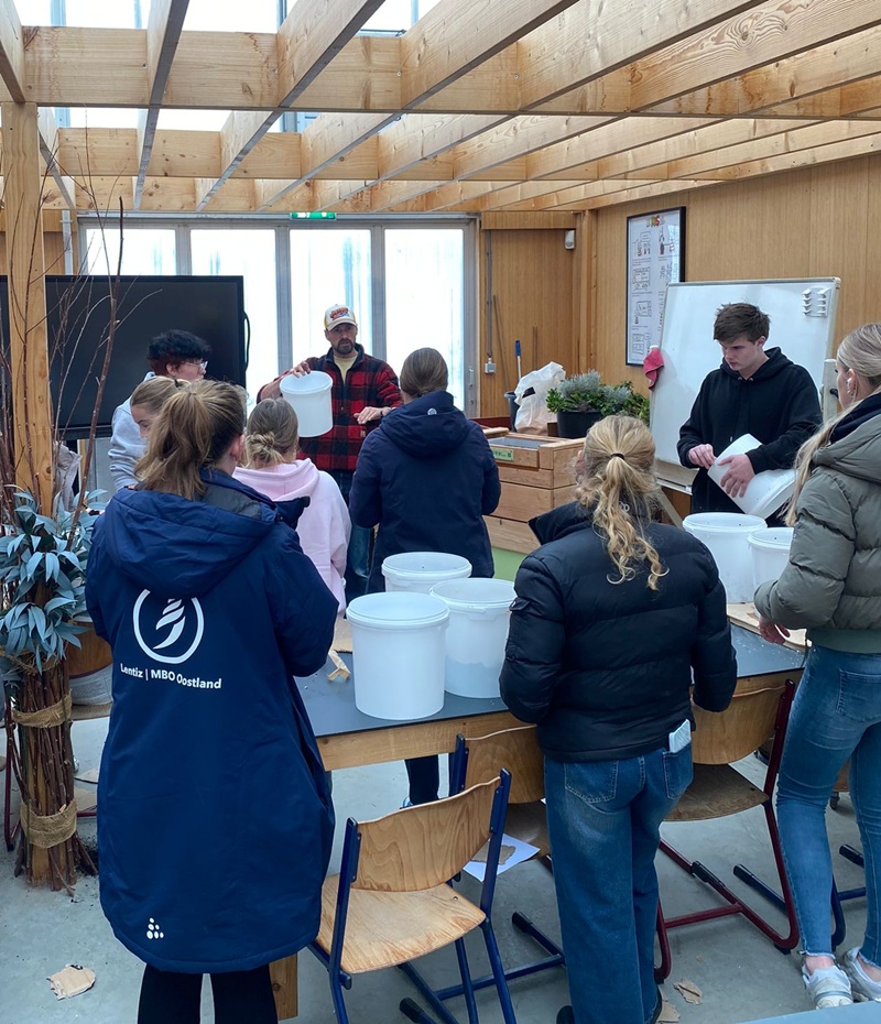 MBO-studenten staan bij een werktafel met emmers