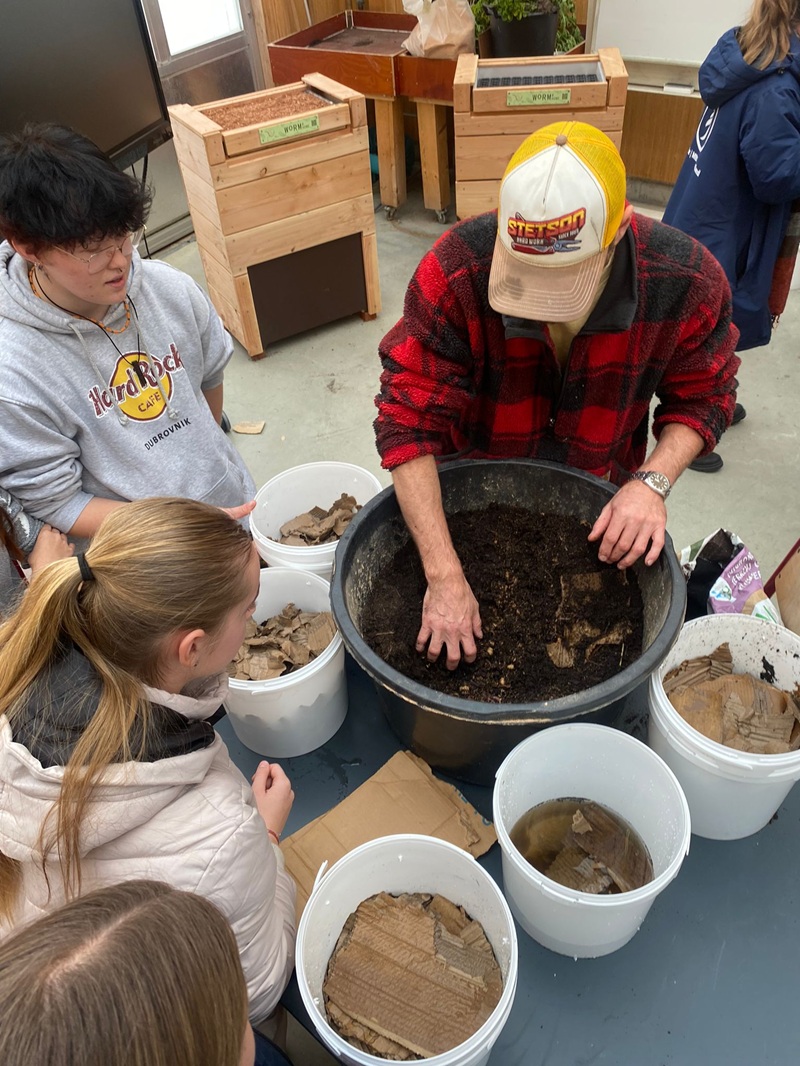 docent en leerlingen met handen in emmers grond