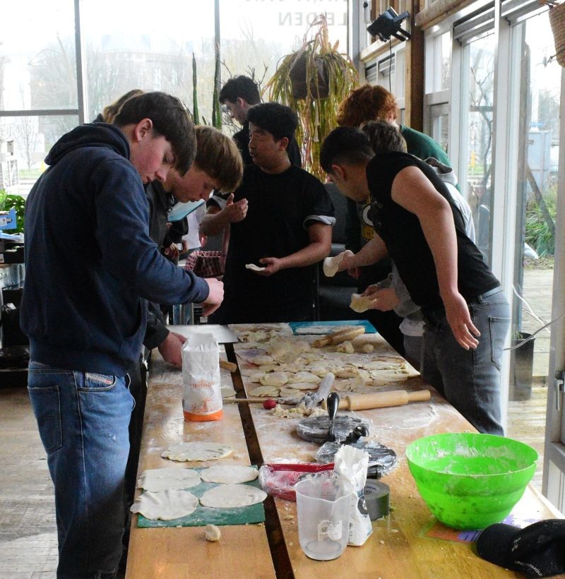 mbo-studenten staan aan een grote tafel te koken